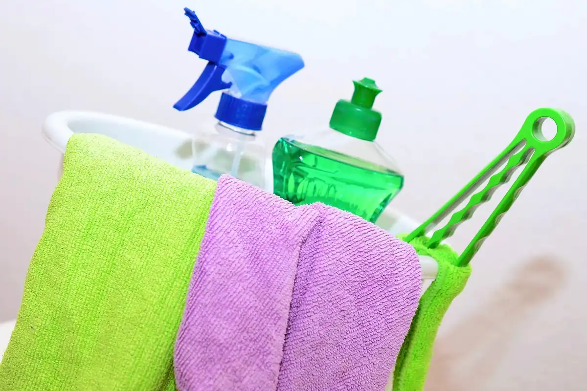Găleată cu lavete colorate, detergent și sticle cu pulverizator pentru curățenie