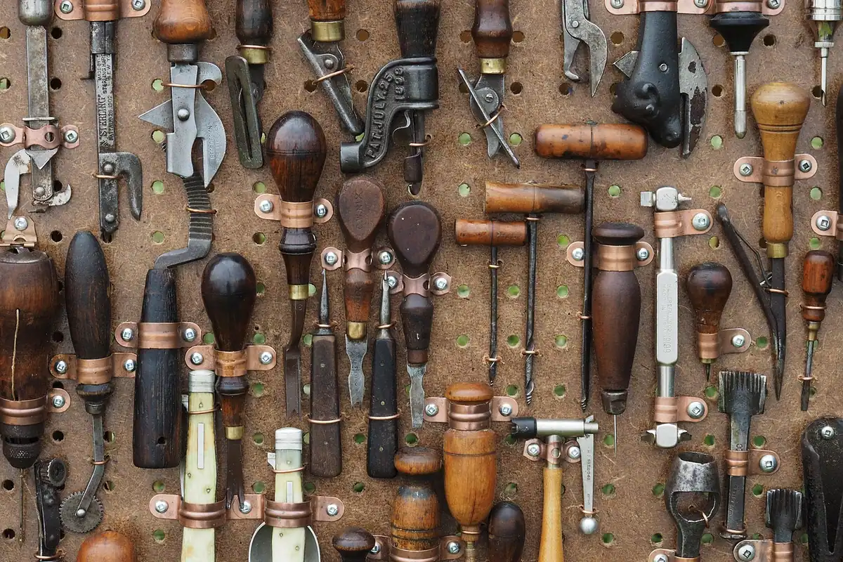 Panou cu unelte vechi de mână, ordonate pe un perete de atelier